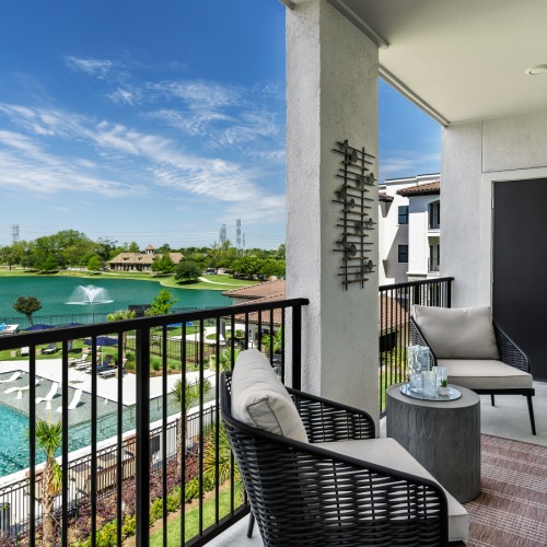 Model porch at our senior living apartments in Sugar Land, TX, featuring outdoor furniture and a view of the pool.