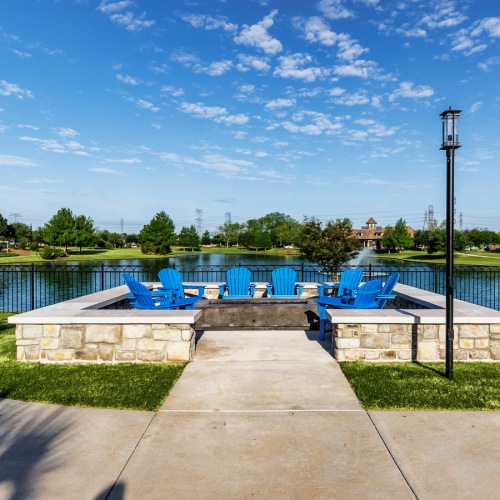 Outdoor lounge at our senior living community in Sugar Land, TX, featuring adirondack chairs surrounding a fire pit.