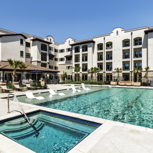 The pool area at our senior living community in Sugar Land, TX, featuring lounge chairs, umbrellas, and tables.